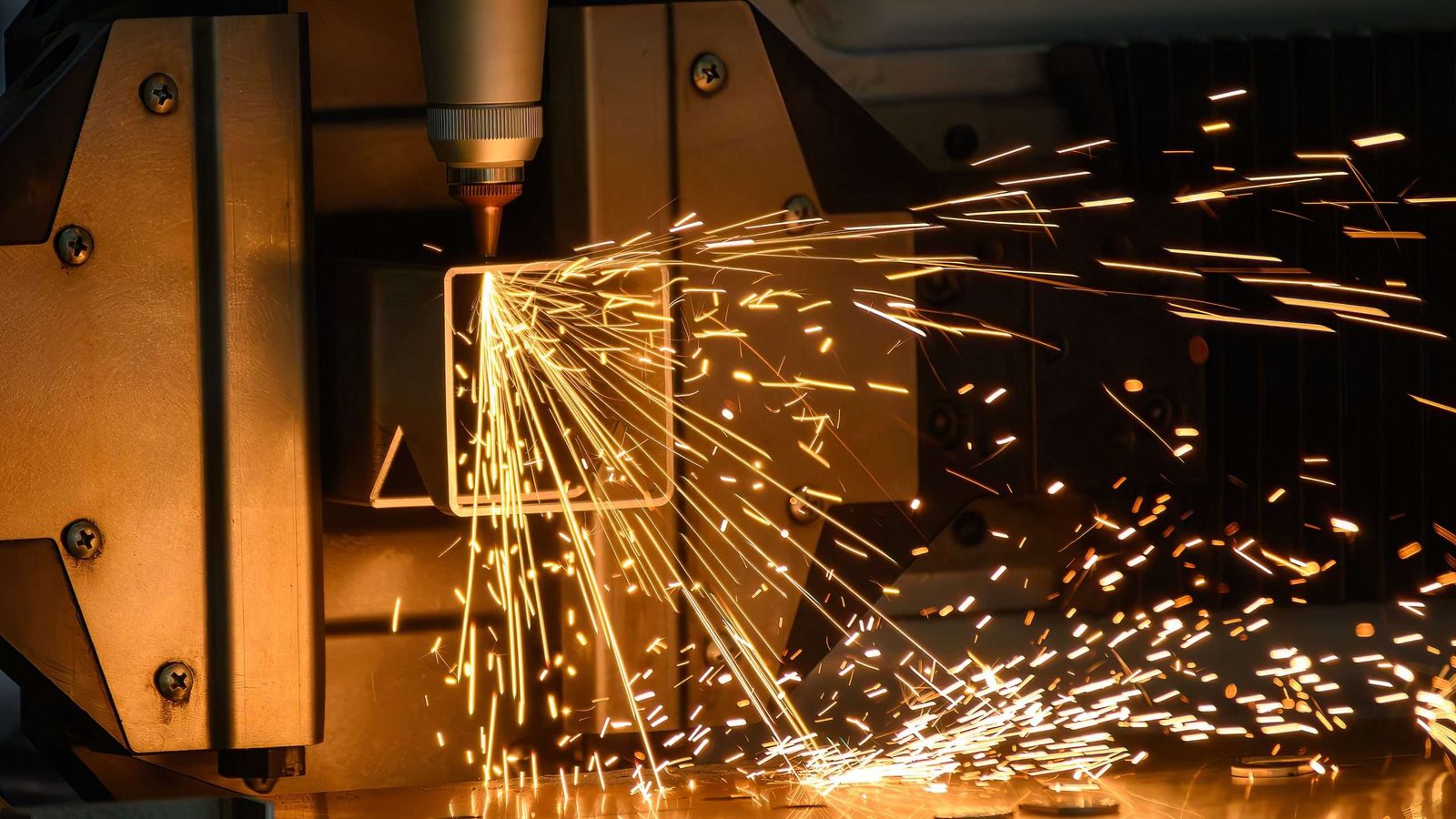 Stock photo: sparks flying from a laser cutting head over a steel plate.